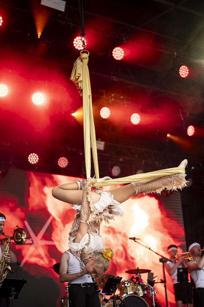 A swayball acrobat suspended in a beam of red light above the stage