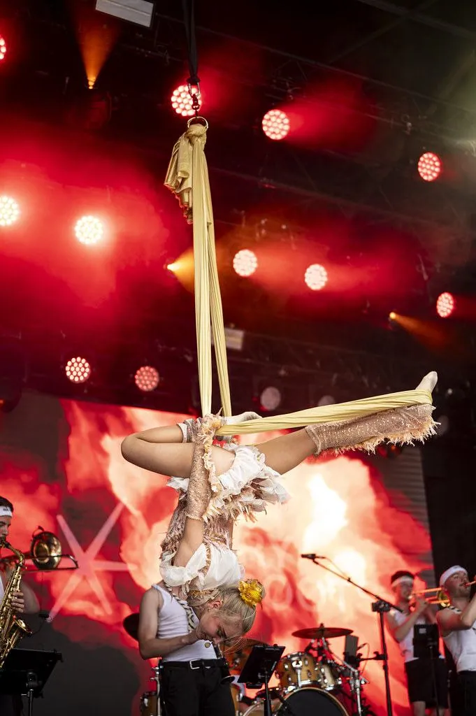 A swayball acrobat suspended in a beam of red light above the stage
