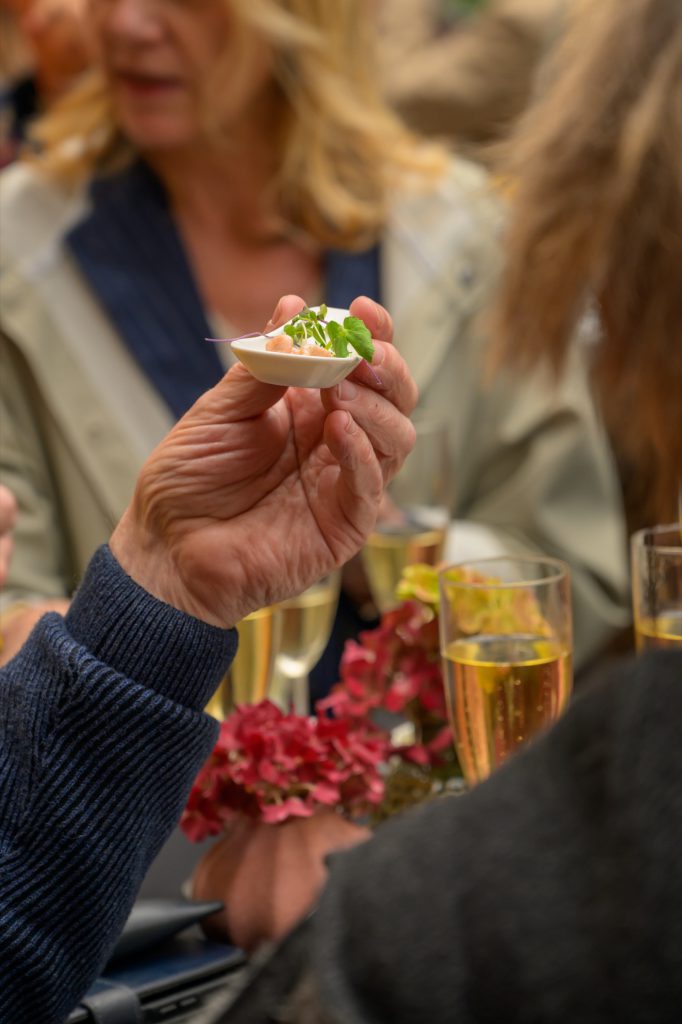 A guest holding a small appetiser, champagne glasses on the table