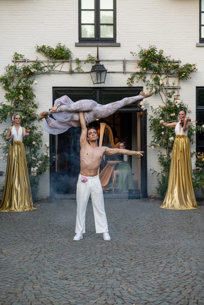 An acrobatic lift in the courtyard of De Barrier, two musicians in gold gowns on either side