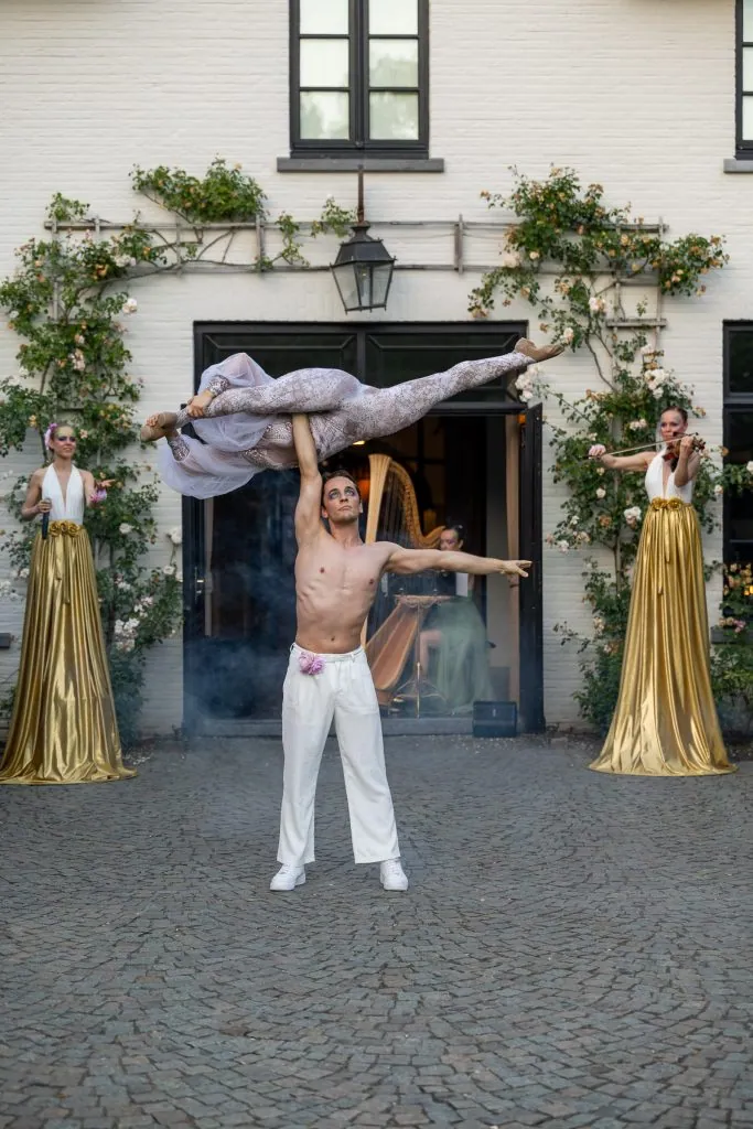 An acrobatic lift in the courtyard of De Barrier, two musicians in gold gowns on either side