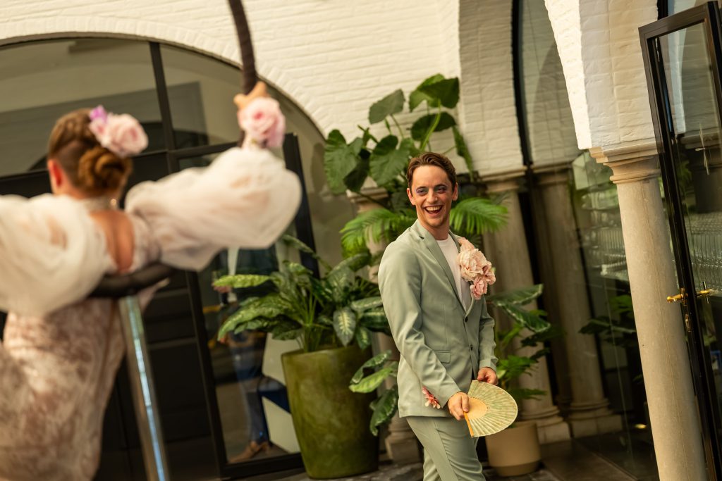 A performer with a fan laughing with guests in a white arcade