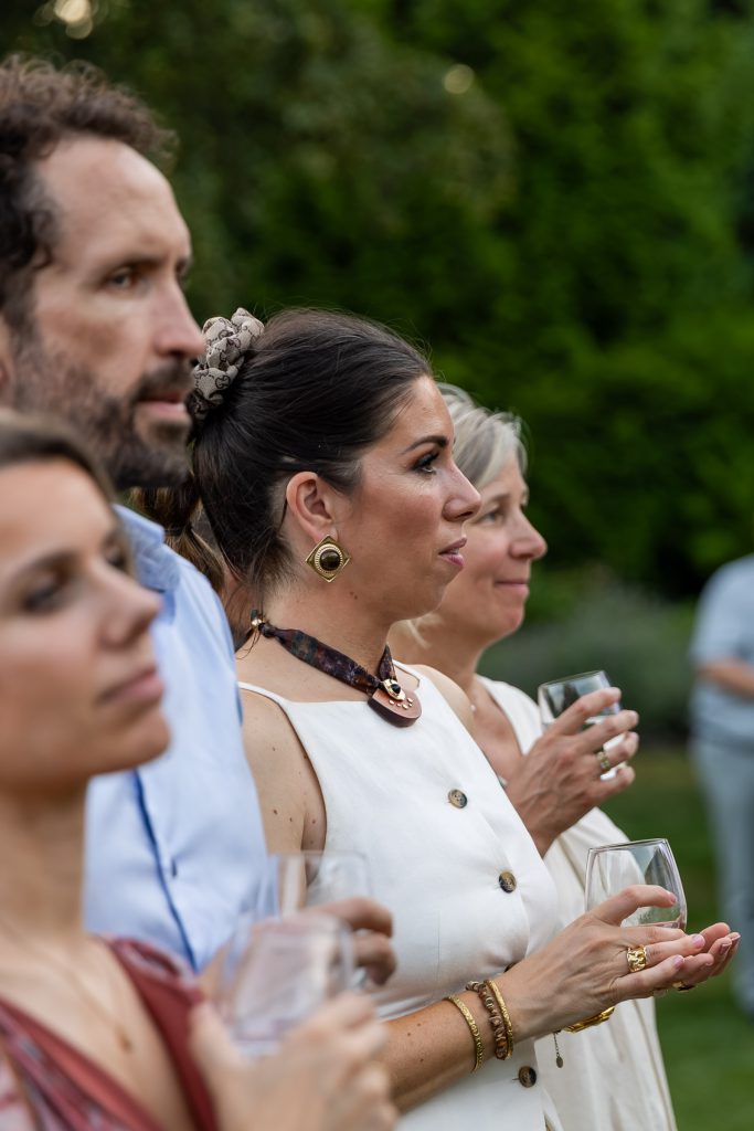 Guests watching the performance in the garden, glasses in hand
