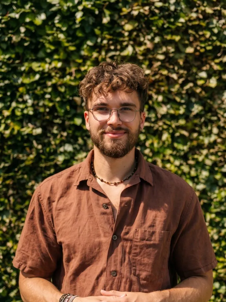 Louka Stouten smiling in front of a green hedge