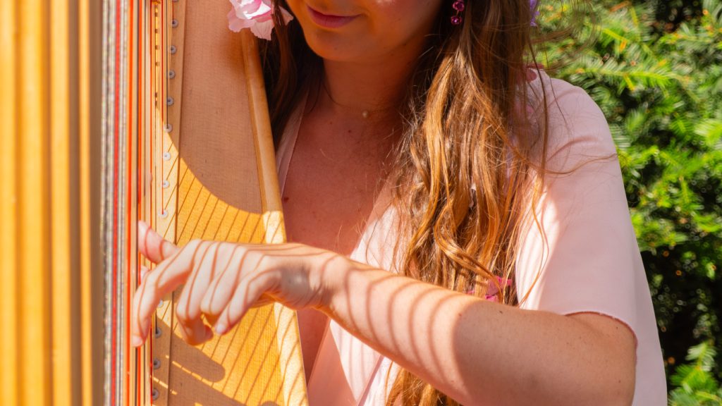 The harpist's hands on the strings, sunlight falling through the harp