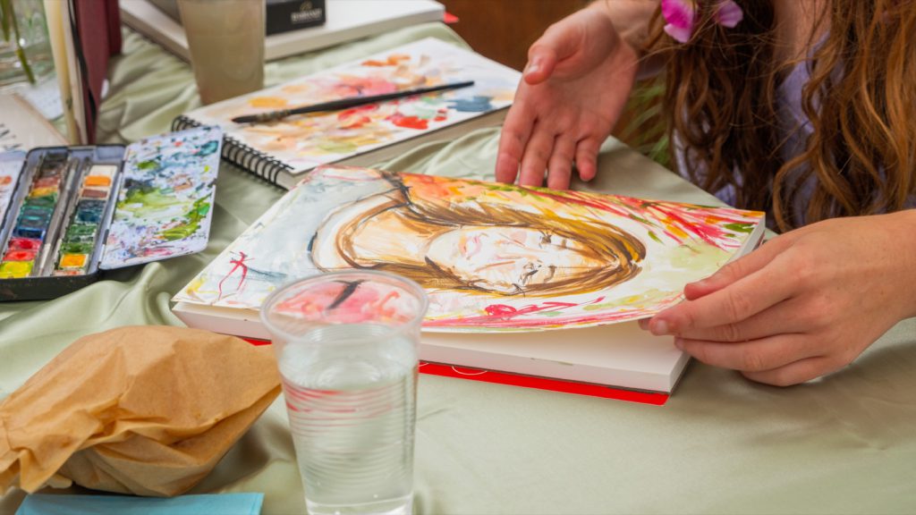 A portrait in watercolour being painted of a guest at one of the stands