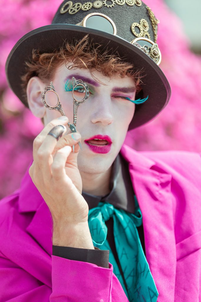 The Mad Hatter in a pink suit and steampunk top hat, peering through a pair of antique spectacles