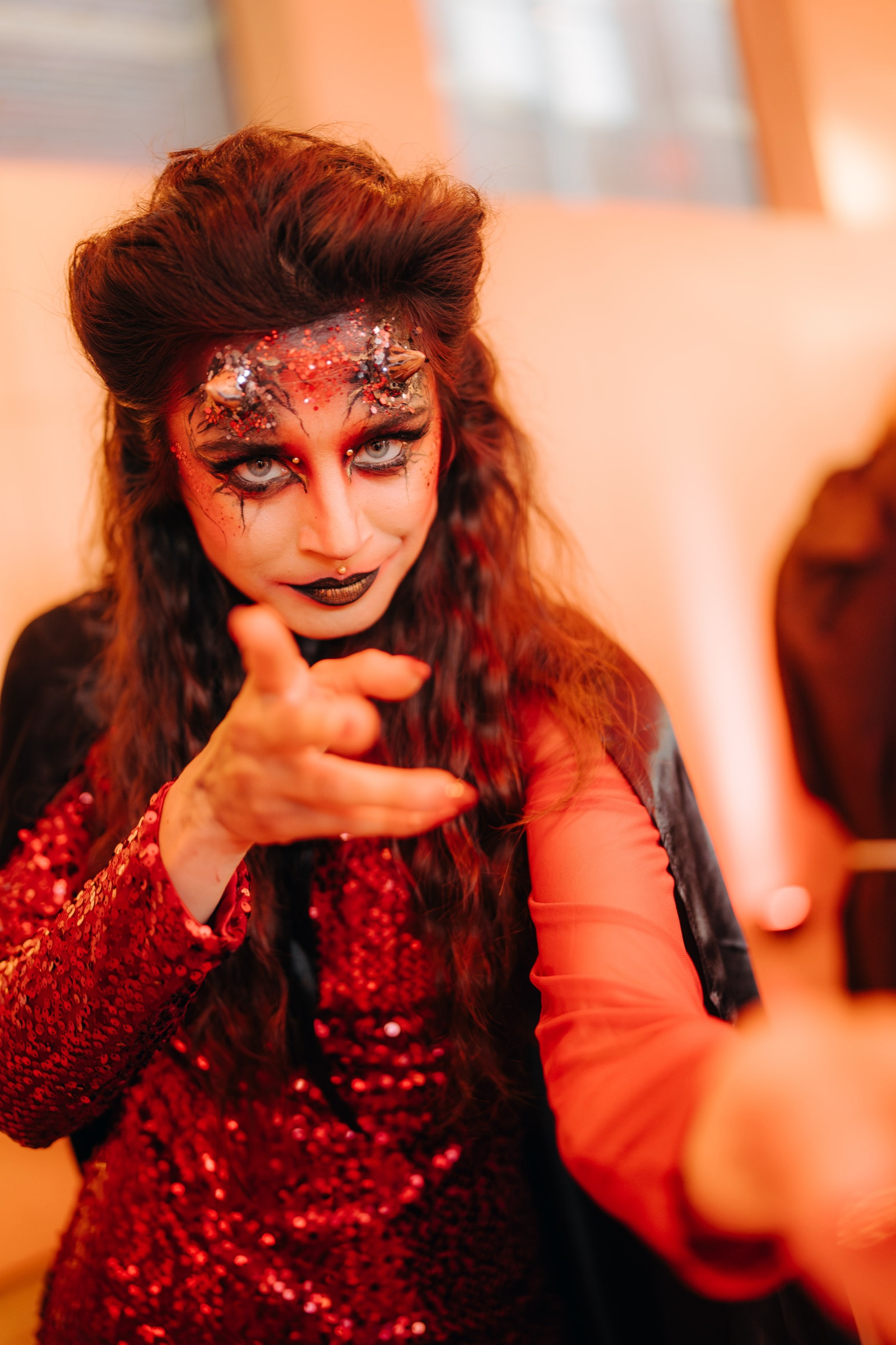 A performer in red sequins and dramatic make-up pointing straight at the camera